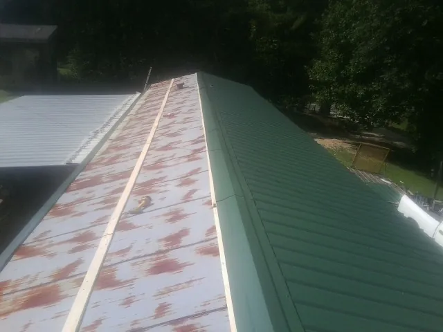 Old rusted panels beside newly installed green metal roofing — Wind Damage Roof Repair by Roofing Brothers in South Vienna