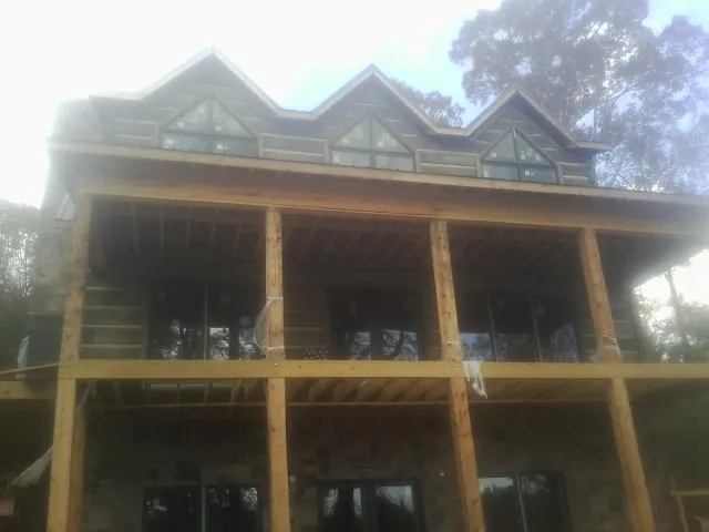 Dormers and porch framing on a large log home under construction — Roof Coating work by our crew in South Vienna