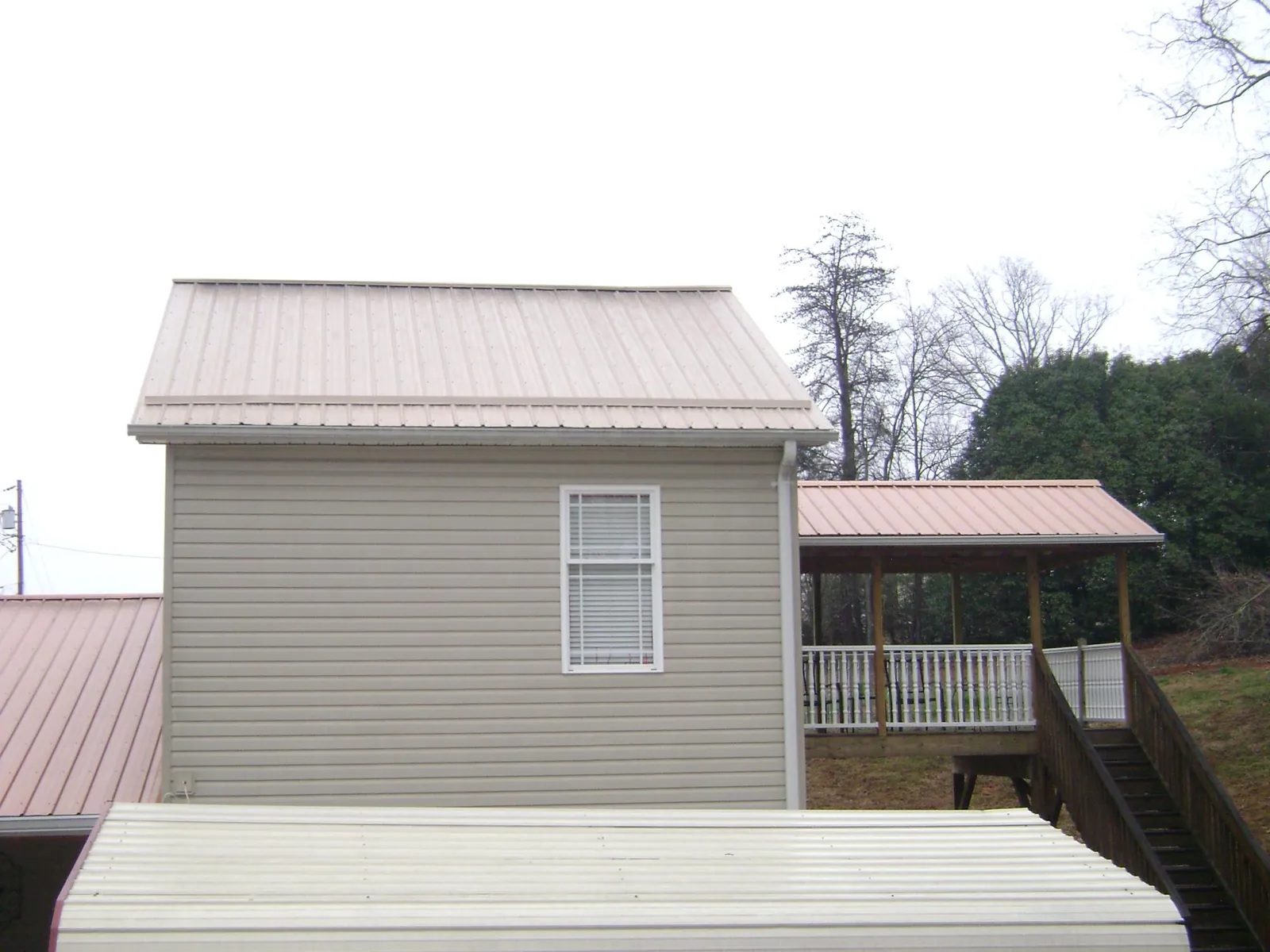 Tan metal roofs on a two story addition and attached porch, from a Roof Replacement job in South Vienna